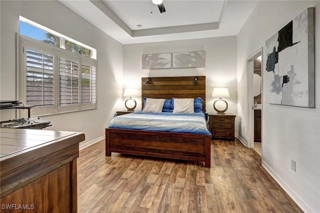 bedroom with ceiling fan, hardwood / wood-style floors, and a tray ceiling