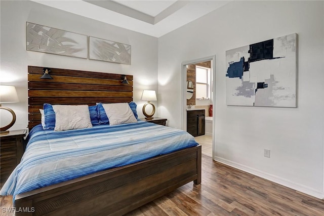 bedroom featuring hardwood / wood-style flooring and connected bathroom