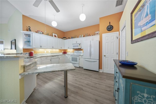 kitchen featuring pendant lighting, white appliances, white cabinets, light wood-type flooring, and kitchen peninsula