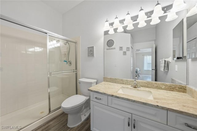 bathroom featuring ceiling fan, hardwood / wood-style floors, an enclosed shower, toilet, and vanity