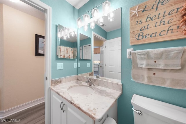 bathroom with wood-type flooring, vanity, and toilet