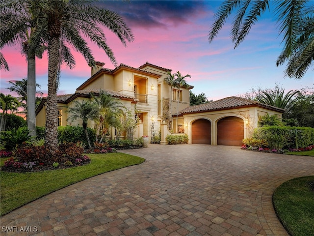 mediterranean / spanish-style home with a garage, a lawn, and a balcony