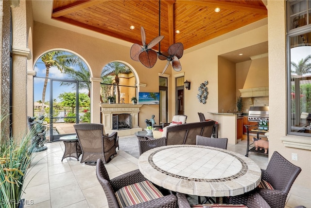 view of patio / terrace with a grill, ceiling fan, an outdoor fireplace, and exterior kitchen