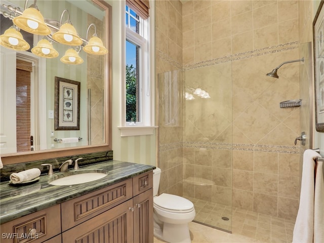 bathroom featuring a tile shower, vanity, and toilet