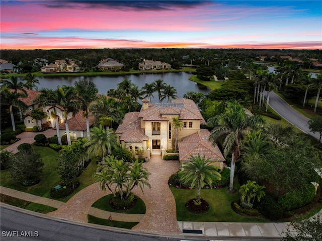 aerial view at dusk featuring a water view