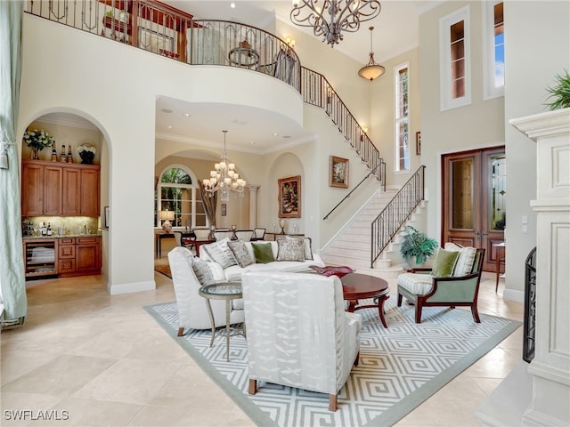 living room featuring ornamental molding, a healthy amount of sunlight, a notable chandelier, and a towering ceiling