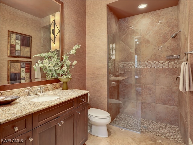 bathroom featuring vanity, a tile shower, tile patterned floors, and toilet