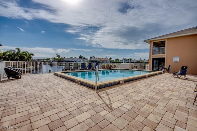 view of swimming pool featuring a patio area and a water view