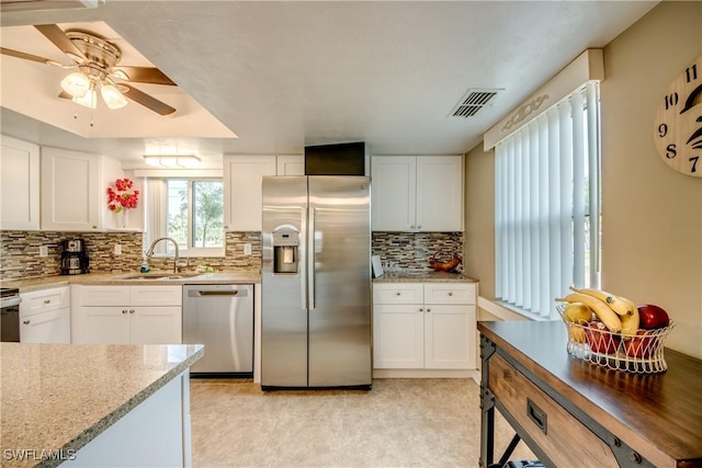 kitchen featuring light stone countertops, white cabinets, appliances with stainless steel finishes, sink, and ceiling fan