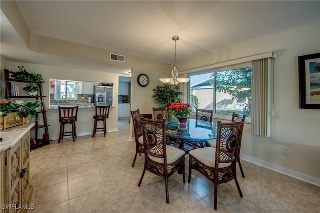 tiled dining space featuring sink and a notable chandelier