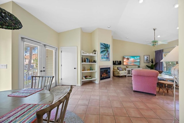 living room with ceiling fan, built in shelves, light tile patterned floors, and vaulted ceiling