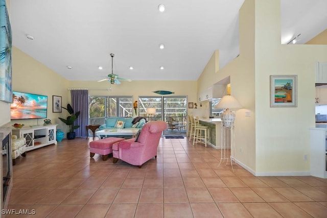 tiled living room with ceiling fan and high vaulted ceiling