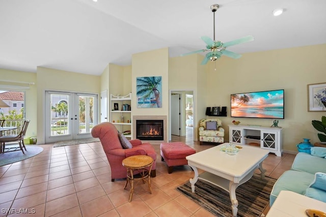 tiled living room with ceiling fan, high vaulted ceiling, and french doors