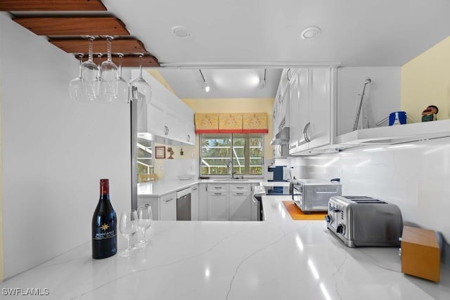 kitchen featuring light stone countertops, appliances with stainless steel finishes, white cabinetry, sink, and kitchen peninsula