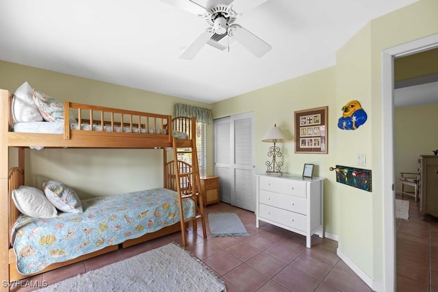 bedroom with ceiling fan, dark tile patterned floors, and a closet