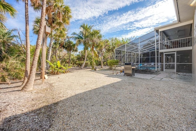 view of yard with ceiling fan, glass enclosure, and a patio