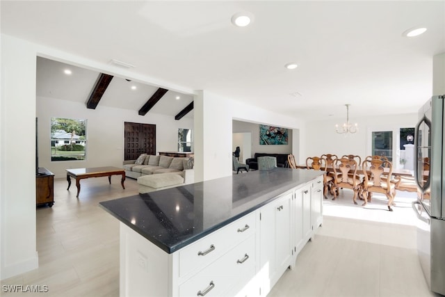 kitchen featuring stainless steel fridge, vaulted ceiling with beams, dark stone countertops, a center island, and white cabinetry