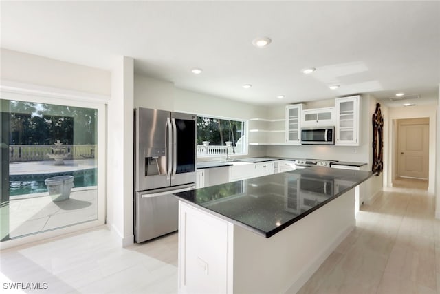 kitchen featuring dark stone counters, white cabinets, sink, a kitchen island, and stainless steel appliances