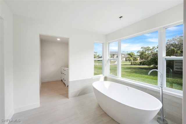 bathroom with a bathing tub, vanity, and tile walls