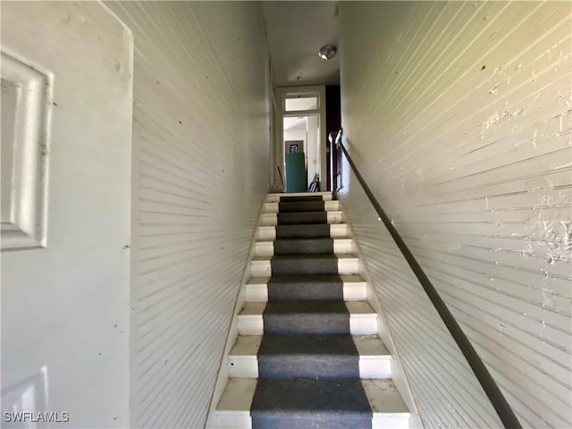 stairway featuring wood walls