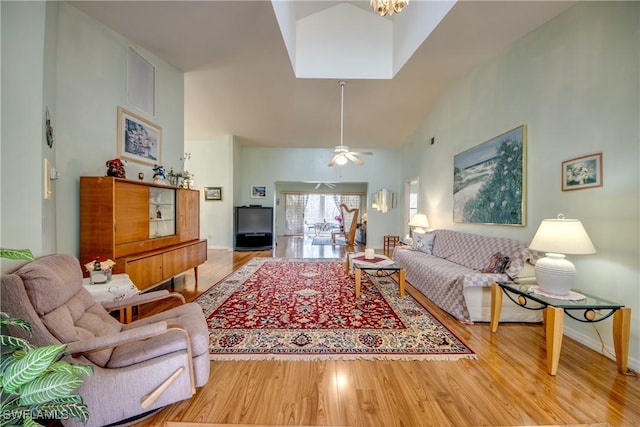 living room featuring a skylight, ceiling fan, high vaulted ceiling, and wood-type flooring