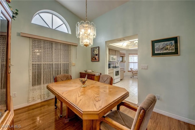 dining area featuring wood-type flooring, high vaulted ceiling, and an inviting chandelier