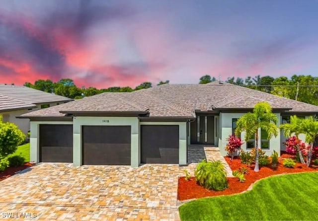 view of front facade featuring decorative driveway, a yard, an attached garage, and stucco siding