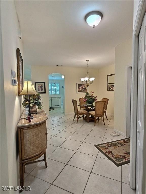 hallway with a chandelier and light tile patterned floors