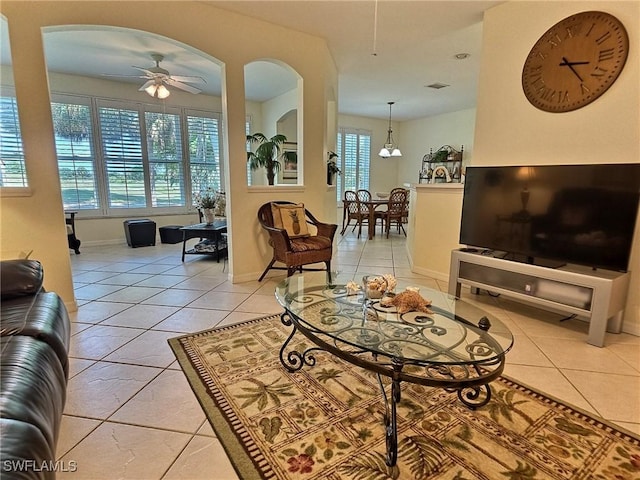 tiled living room with ceiling fan with notable chandelier