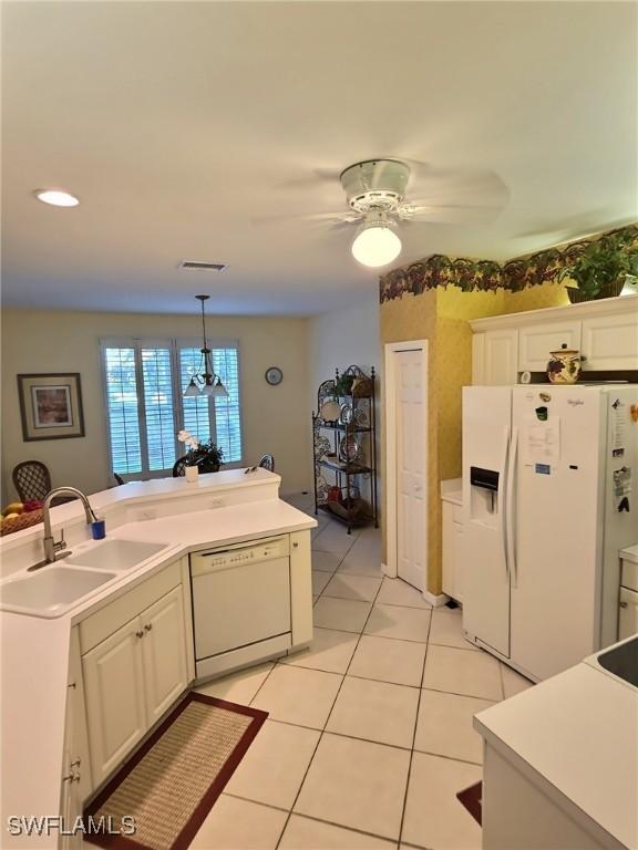 kitchen with white appliances, sink, white cabinets, decorative light fixtures, and ceiling fan with notable chandelier