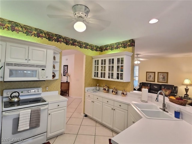 kitchen with sink, white cabinets, white appliances, light tile patterned floors, and kitchen peninsula