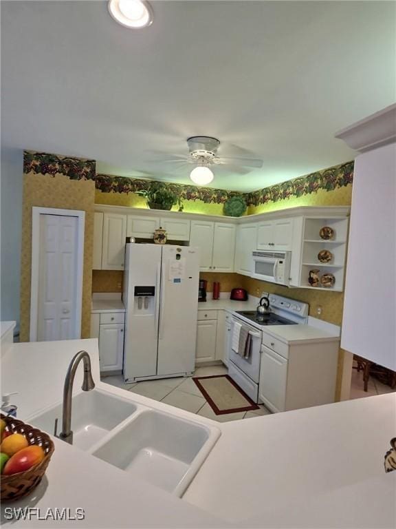 kitchen with white appliances, light tile patterned floors, white cabinets, ceiling fan, and sink