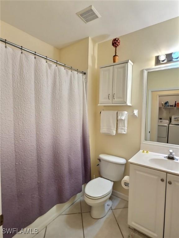 bathroom with toilet, washing machine and clothes dryer, tile patterned floors, and vanity