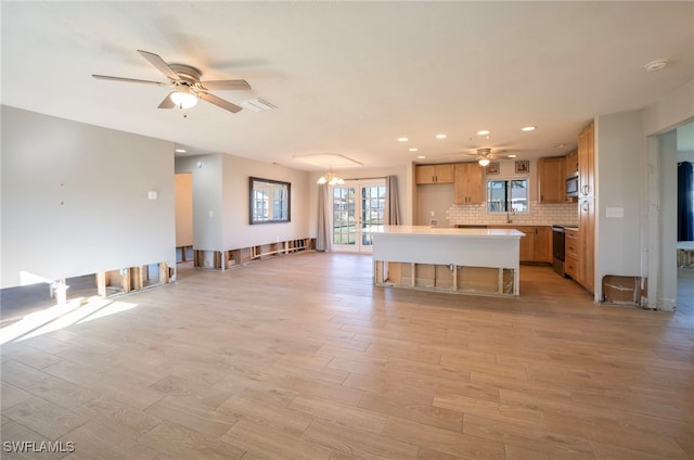 kitchen featuring decorative backsplash, a center island, stainless steel appliances, and ceiling fan with notable chandelier