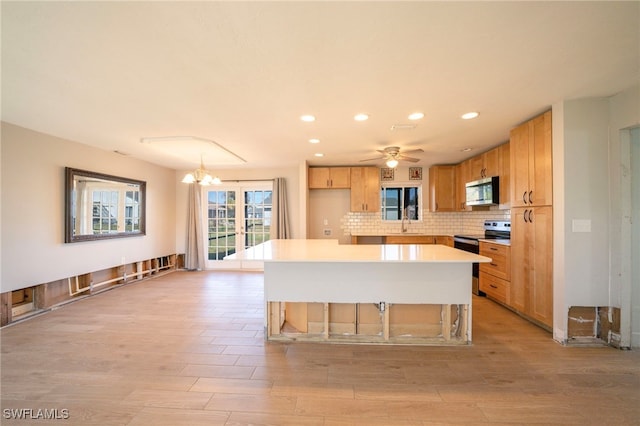 kitchen with stainless steel appliances, a center island, decorative backsplash, and light wood-type flooring