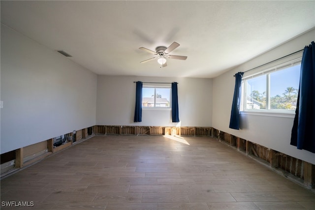 empty room with hardwood / wood-style flooring, plenty of natural light, and ceiling fan