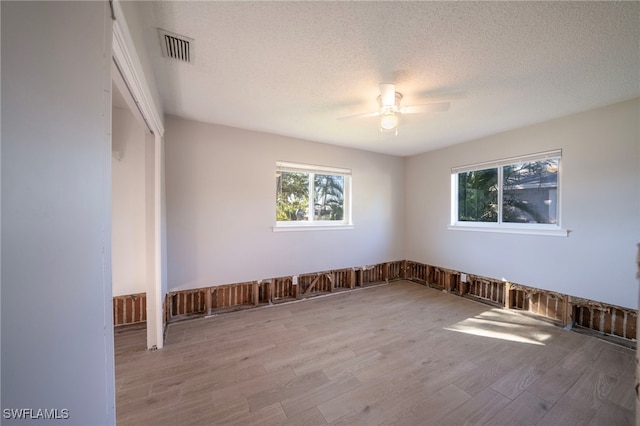 unfurnished room featuring a textured ceiling, light hardwood / wood-style floors, and ceiling fan