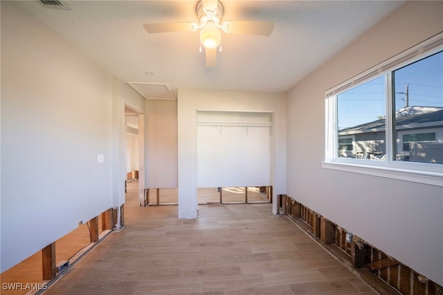 interior space featuring ceiling fan, a textured ceiling, and light hardwood / wood-style flooring