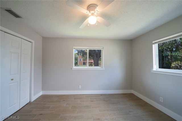 6080 Park Rd, Fort Myers, FL 33908 - unfurnished bedroom featuring multiple windows, a closet, wood finished floors, a textured ceiling, and baseboards