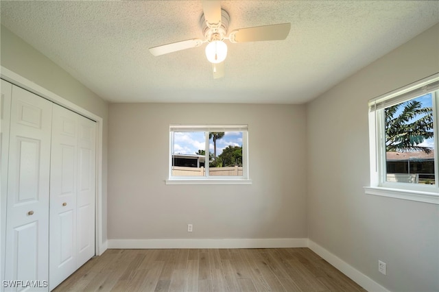 6080 Park Rd, Fort Myers, FL 33908 - unfurnished bedroom with multiple windows, wood finished floors, a closet, and a textured ceiling