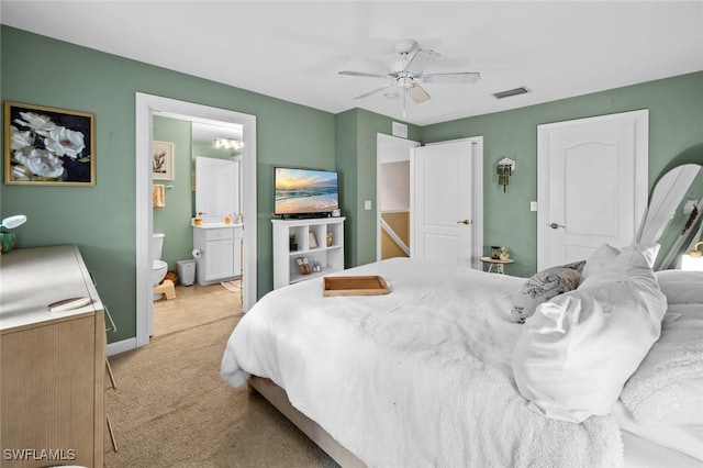 bedroom with ceiling fan, light carpet, and ensuite bath