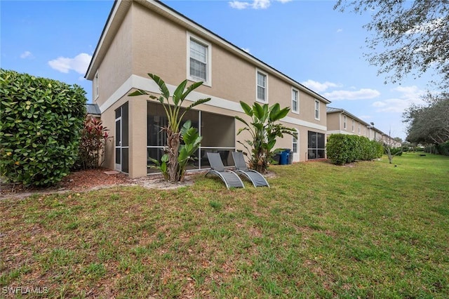 rear view of house featuring a sunroom and a yard