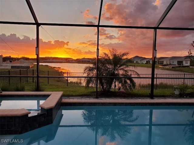 pool at dusk featuring a lanai and a water view