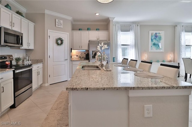 kitchen with appliances with stainless steel finishes, sink, white cabinetry, and an island with sink