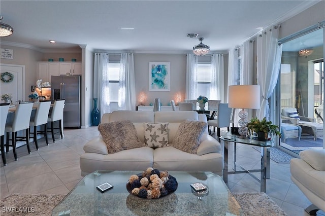 living room with light tile patterned floors, ornamental molding, and an inviting chandelier