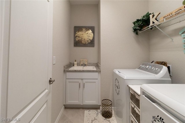 laundry area featuring light tile patterned floors, independent washer and dryer, and sink