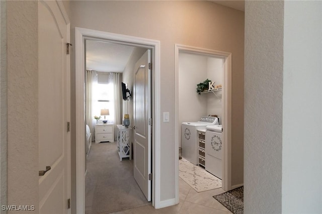 corridor with light tile patterned flooring and separate washer and dryer