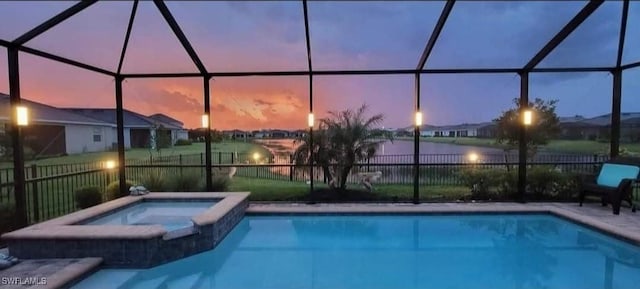 pool at dusk with an in ground hot tub, a lanai, and a water view