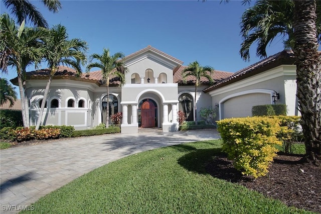 mediterranean / spanish home featuring a garage and a front lawn