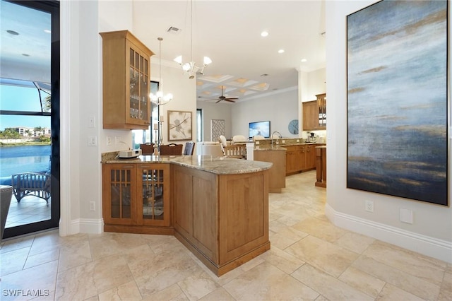 kitchen featuring kitchen peninsula, light stone counters, coffered ceiling, crown molding, and pendant lighting